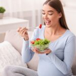 Pregnant woman eating healthy food at home during pregnancy for balanced trimester-wise nutrition
